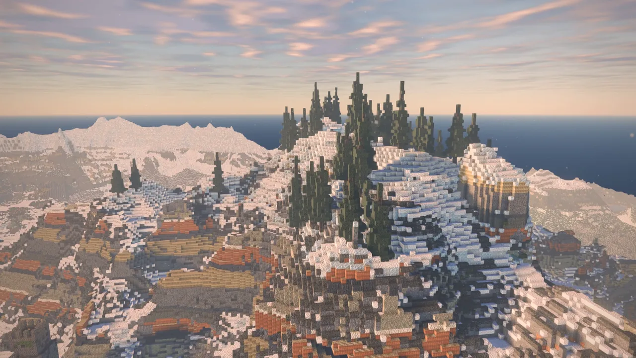 A snowy mountain range with pine on its slopes and the sea behind